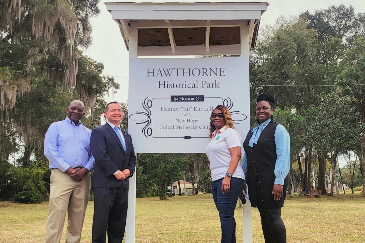 The City Commissioners and the Mayor Jacquelyn Randall standing in front of the new museum park sign.
